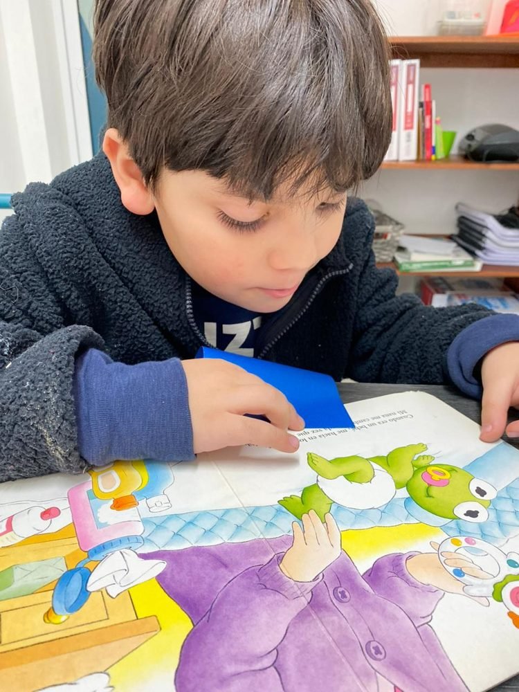 Un alumno mira con atención las páginas ilustradas de un cuento
