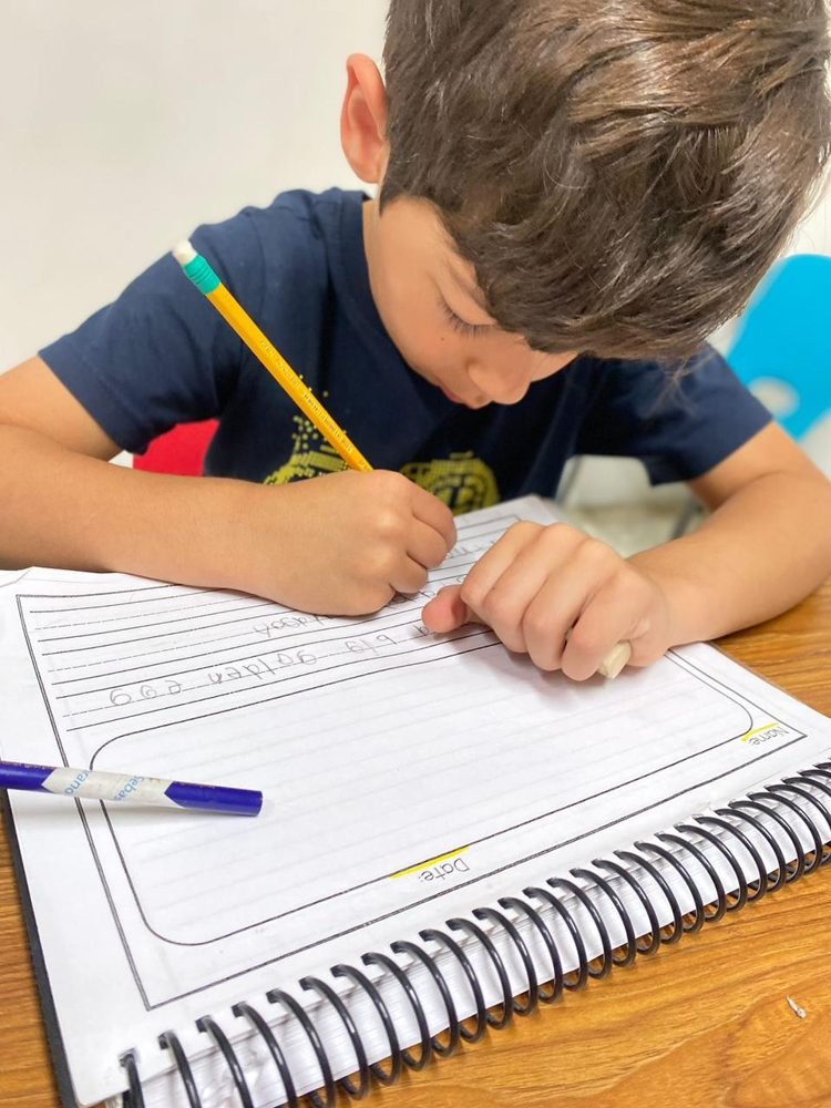 Un alumno escribe con lápiz en un cuaderno de espiral