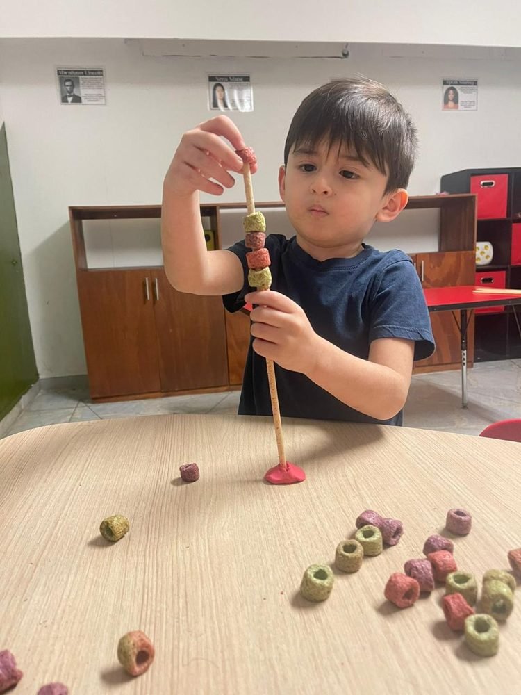 Un alumno ensarta cuentas de colores en una varilla
