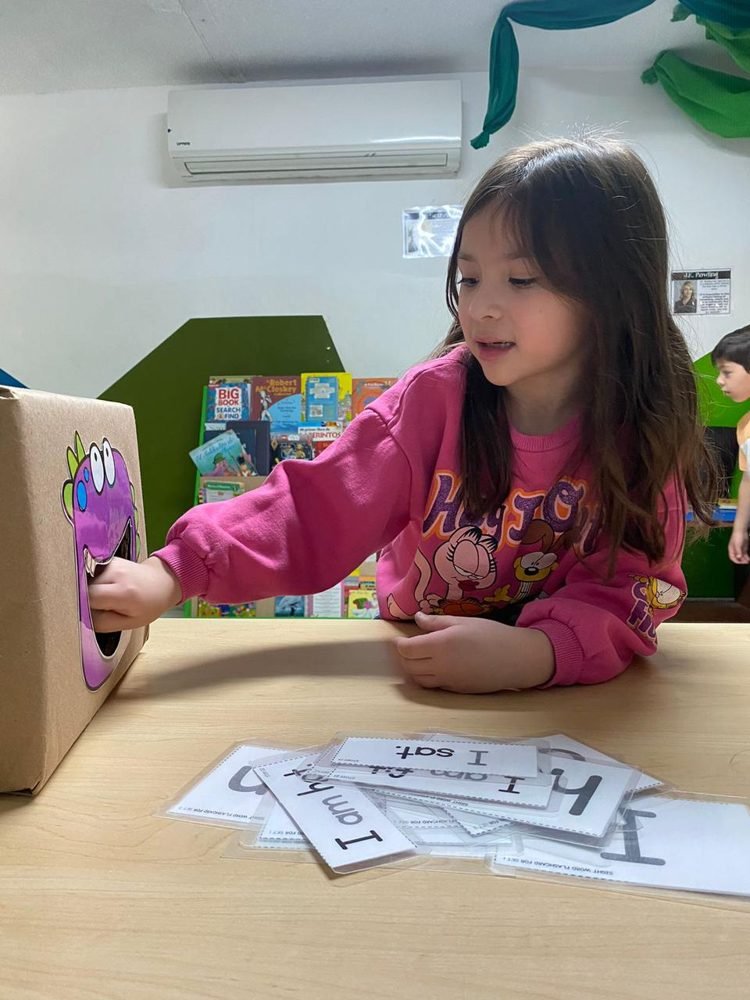 Una alumna acomoda tarjetas con palabras en inglés sobre una mesa