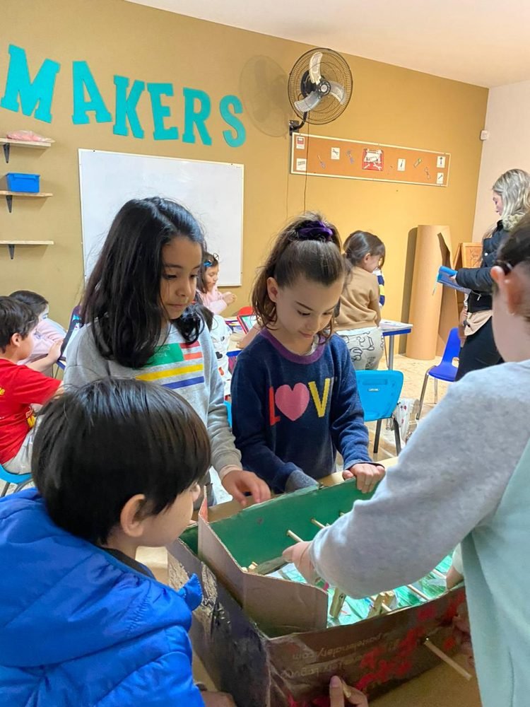 Alumnos construyen juntos con cartón y palitos en el rincón Makers del salón